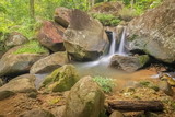 view nature of silky stream water flowing around with many arch rocks and green forest background, Phong Phra Bat Waterfall, Chiang Rai, northern of Thailand.