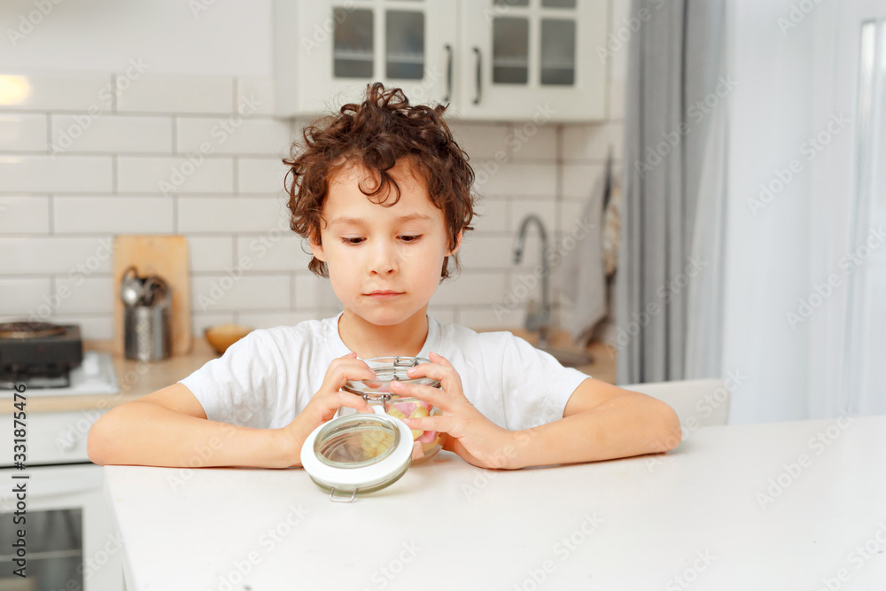 boys real brothers in a bright kitchen eating marshmellow from a glass jar boys real brothers in a bright kitchen eating marshmellow from a glass jar
