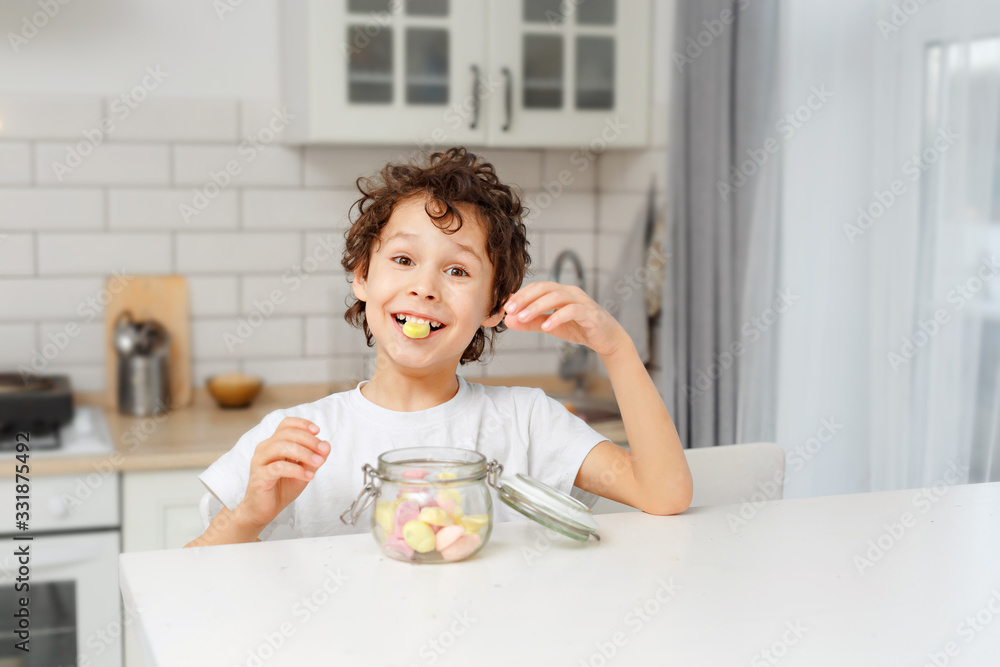 boys real brothers in a bright kitchen eating marshmellow from a glass jar boys real brothers in a bright kitchen eating marshmellow from a glass jar
