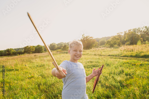 Closeup view portrait of healthy happy brave white kid playing wooden vintage toys outdoors in sunset golden scenic field landscape. photo