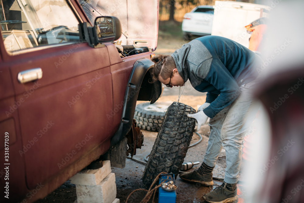 A man repairs a car, puts wheels, changes seasonal tires