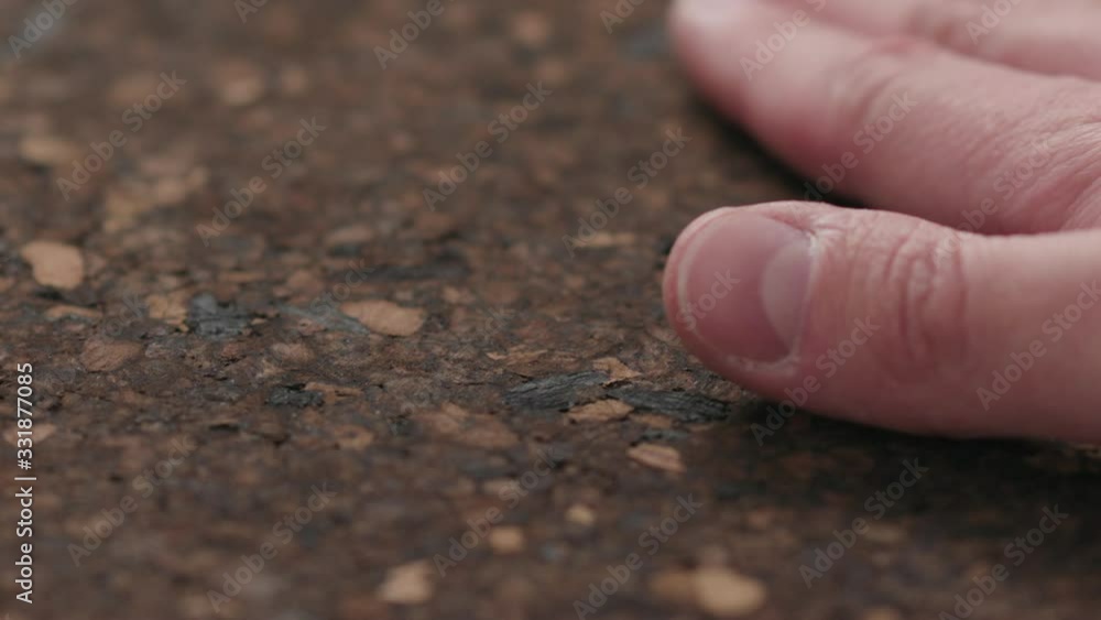 Slow motion man hands touch dark cork surface with oil finish Slow motion man hands touch dark cork surface with oil finish