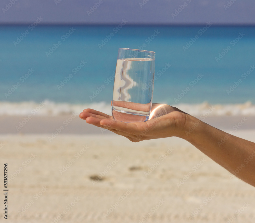 Glass of water. Hot beach day. A glass of water in female hands. Glass of water. Hot beach day. A glass of water in female hands.