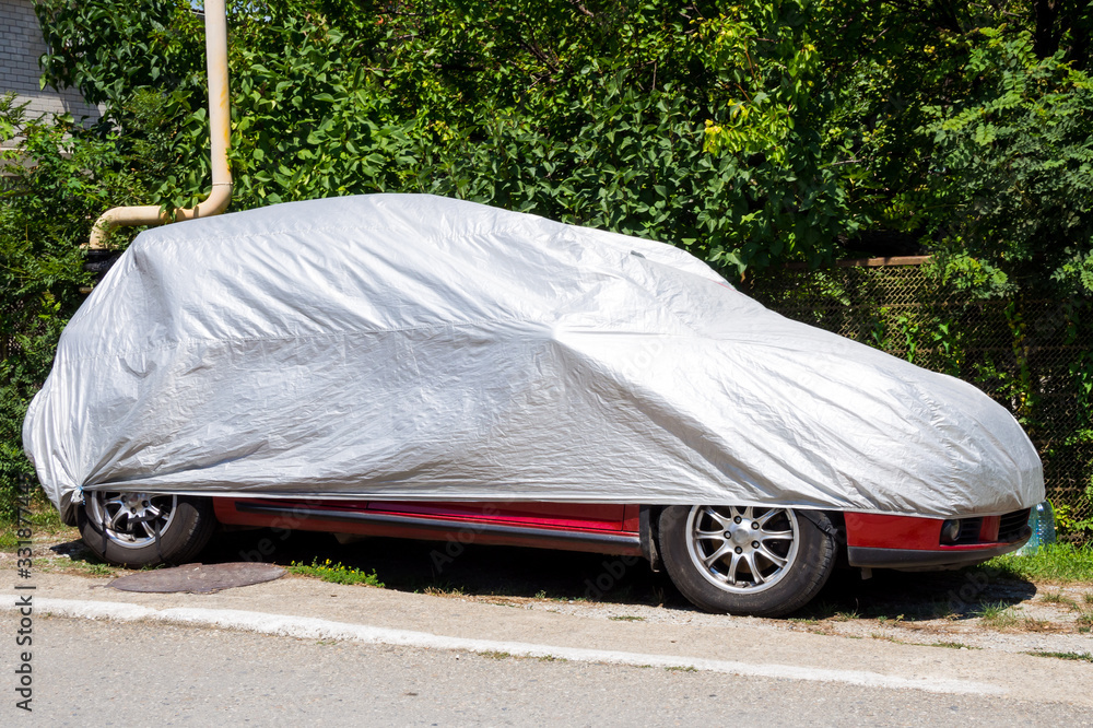 The car is on the side of the road under a protective cover