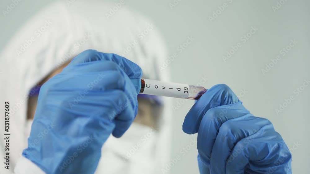 Coronavirus Covid 19 infected blood sample in sample tube in hand of male scientist biohazard protection clothing in coronavirus covid 19 research laboratory, Coronavirus Covid 19 infected blood sample in sample tube in hand of male scientist biohazard protection clothing in coronavirus covid 19 research laboratory,