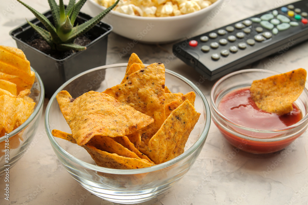 Popcorn and various snacks and a tv remote control on a light concrete table. Concept of watching a movie or video at home. Popcorn and various snacks and a tv remote control on a light concrete table. Concept of watching a movie or video at home.