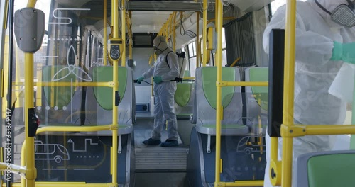 HazMat team in protective suits decontaminating public transport, bus interior during virus outbreak photo