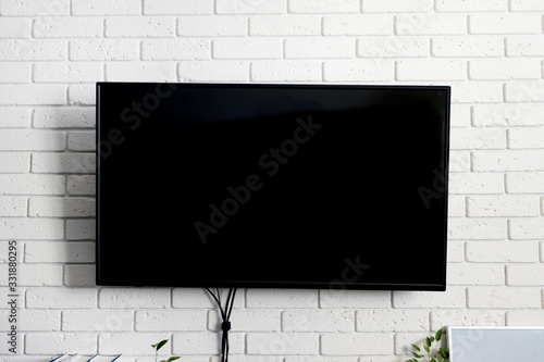 Led tv black color on brick white wall  indoors. Living room. Concept rest at home