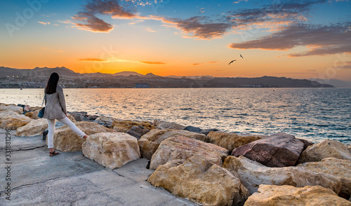 Colorful sunset at the Red Sea; view from stone walking pier on central beach...
