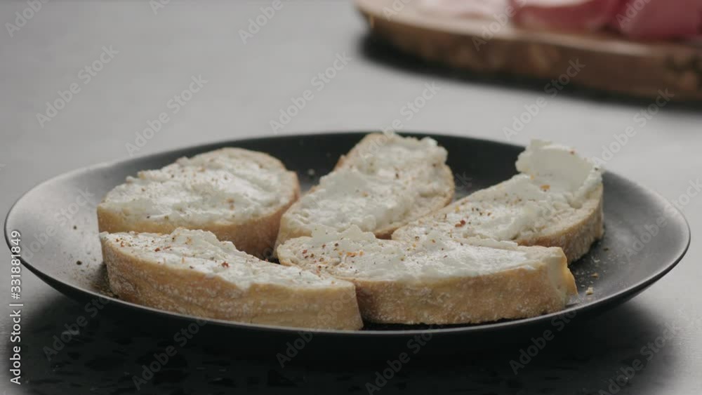 Slow motion of seasoning ricotta cheese on ciabatta slices Slow motion of seasoning ricotta cheese on ciabatta slices