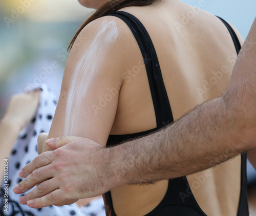 A man applies sunblock to the girl’s back.