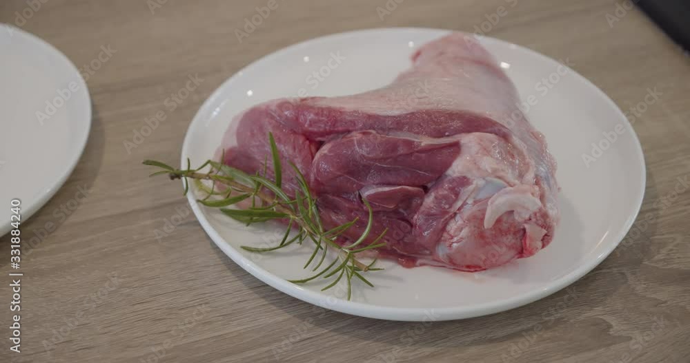 Raw lamb shank with rosemary herb on plate, Close up Raw lamb shank with rosemary herb on plate, Close up
