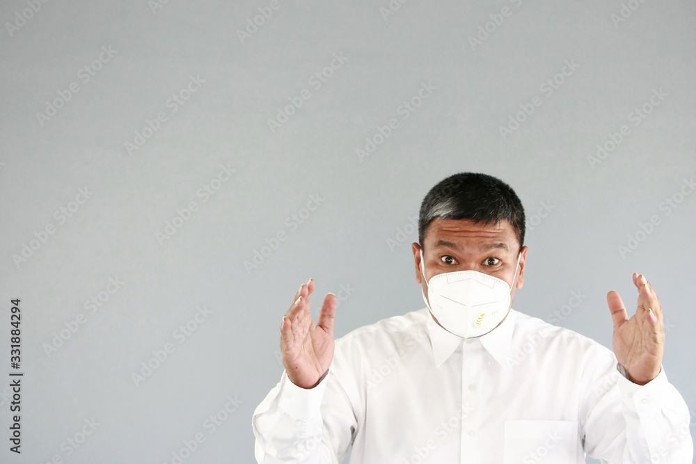 A asian man age 43 years with white shirt , wearing a mask Prevent germs Covid-19 , on gray background A asian man age 43 years with white shirt , wearing a mask Prevent germs Covid-19 , on gray background