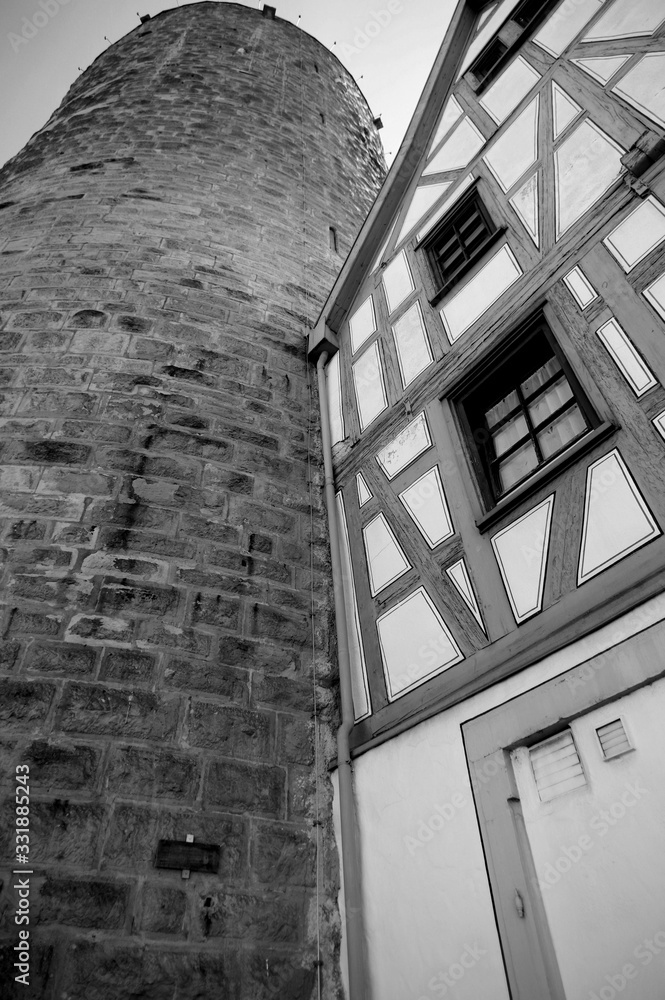 Gepflegtes Fachwerkhaus neben uraltem Wachturm in schwarz-weiß