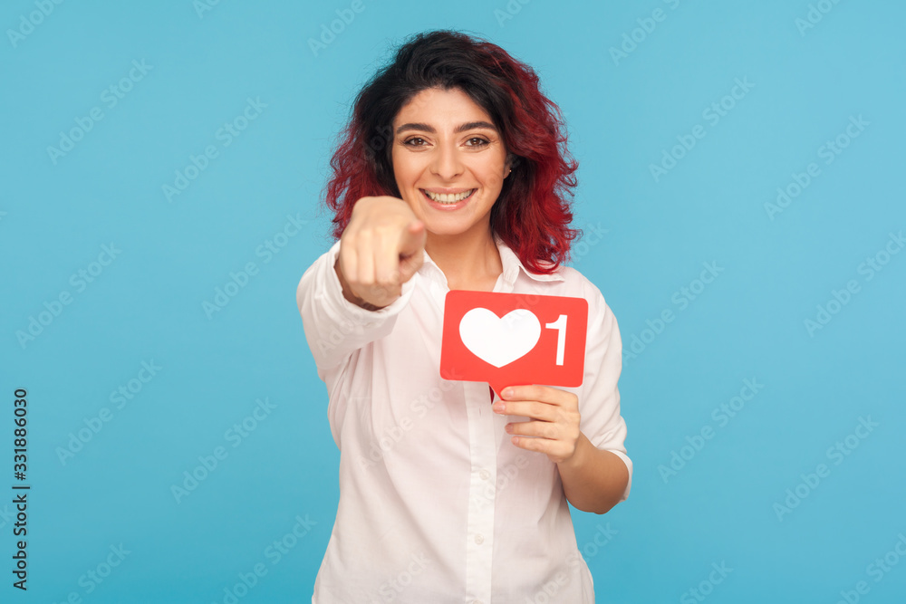 You push Like button of social media! Portrait of pretty girl with fancy red hair holding heart icon and pointing to camera, recommending to follow and share blog with interesting content. studio shot You push Like button of social media! Portrait of pretty girl with fancy red hair holding heart icon and pointing to camera, recommending to follow and share blog with interesting content. studio shot
