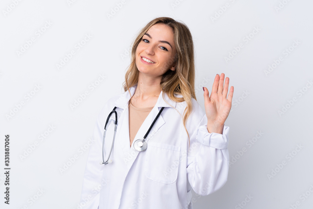 Young woman over isolated white background wearing a doctor gown and saluting Young woman over isolated white background wearing a doctor gown and saluting