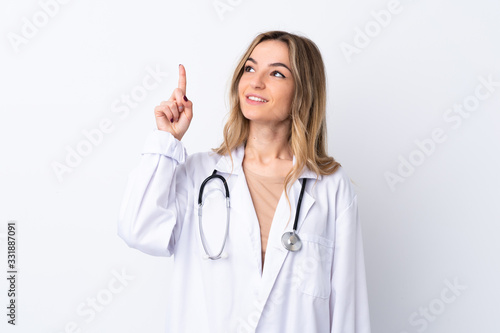 Young woman over isolated white background wearing a doctor gown and pointing up