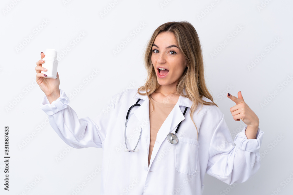 Young woman over isolated white background wearing a doctor gown and holding pills Young woman over isolated white background wearing a doctor gown and holding pills