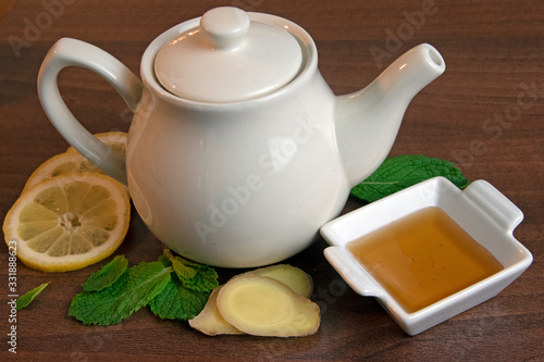Close-up of ginger, mint, honey and lemon surrounding teapot