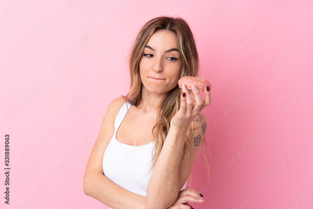 Young woman over isolated pink background holding a donut Young woman over isolated pink background holding a donut