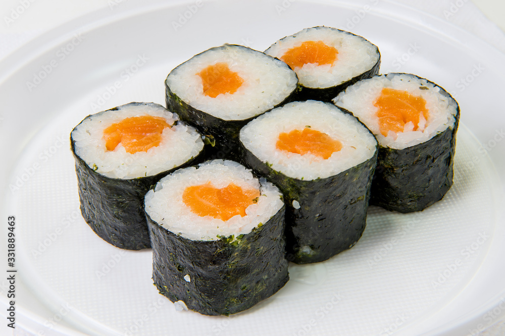Traditional Japanese rolls of seaweed, rice and salmon on a plastic disposable plate on a white background Traditional Japanese rolls of seaweed, rice and salmon on a plastic disposable plate on a white background