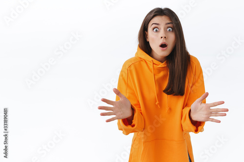 Startled and shocked young woman stand in stupor catching ball, gasping open mouth and stare popped eyes camera, raise hands up something flying at her, stand white background