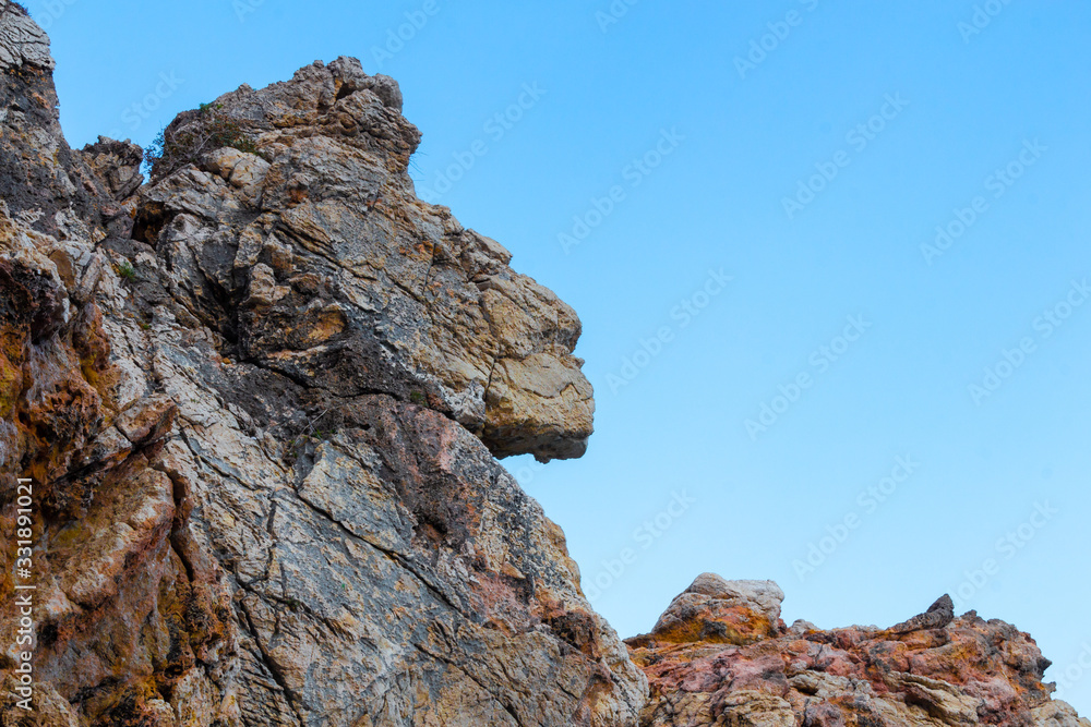 Rock in the shape of lion head against serene blue sky Rock in the shape of lion head against serene blue sky
