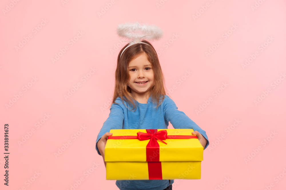 Portrait of generous kind angelic little girl with nimbus giving big birthday present to camera and smiling, congratulating on holiday, sharing gift. indoor studio shot isolated on pink background Portrait of generous kind angelic little girl with nimbus giving big birthday present to camera and smiling, congratulating on holiday, sharing gift. indoor studio shot isolated on pink background