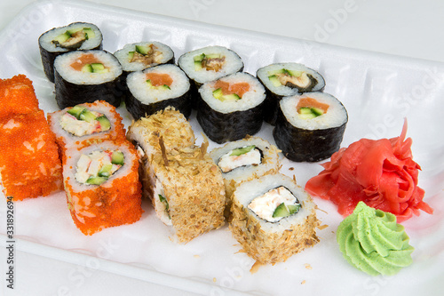 A set of three types of rolls with salmon, crab sticks, breaded cheese, as well as wasabi and ginger on a disposable plastic plate