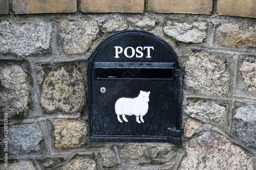 Detalle de un buzón postal en Irlanda con una oveja blanca grabada en metal