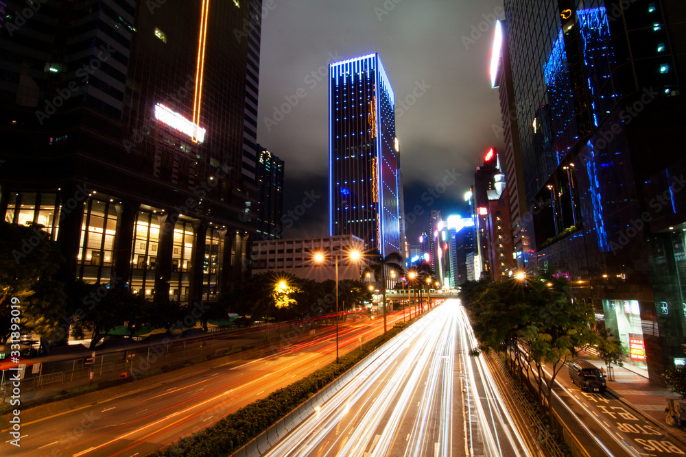 Long exposure shot with trailing lights of busy traffic at night in Hong Kong with lighted skyscrapers in the background