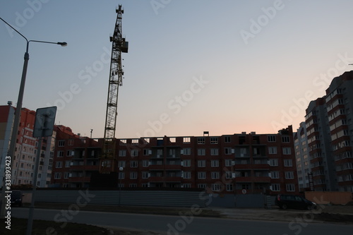 unfinished building near which there is a construction crane against the blue sky