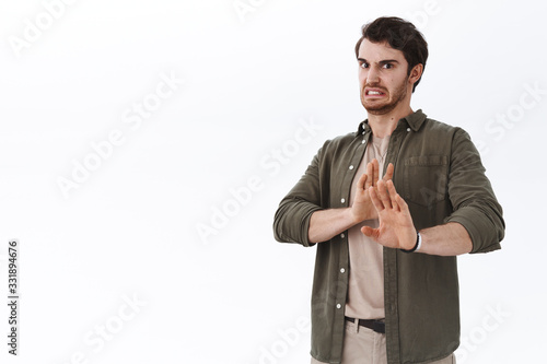 Disgusted reluctant bearded man grimacing from aversion, turn away displeased, avoid something awful, raising hands in stop, no or prohibition gesture, rejecting disgusting thing, white background photo