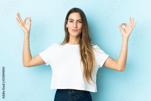 Young caucasian woman over isolated background in zen pose