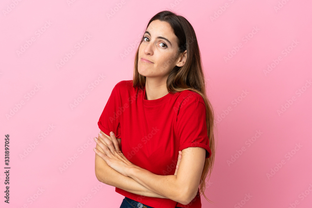 Fototapeta premium Young caucasian woman isolated on pink background making doubts gesture while lifting the shoulders