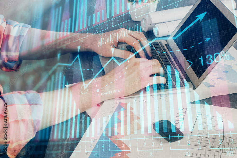 Double exposure of stock graph with businessman typing on computer in office on background. Concept of hard work.