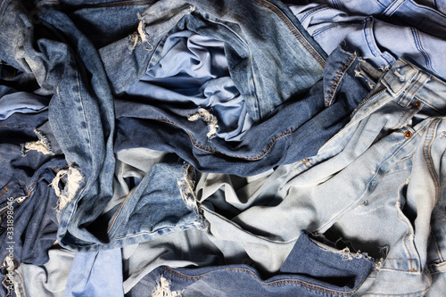 Different blue colored female jeans mixed, messy pile of navy jeans. Textile consumerism, many clothes are not used photo