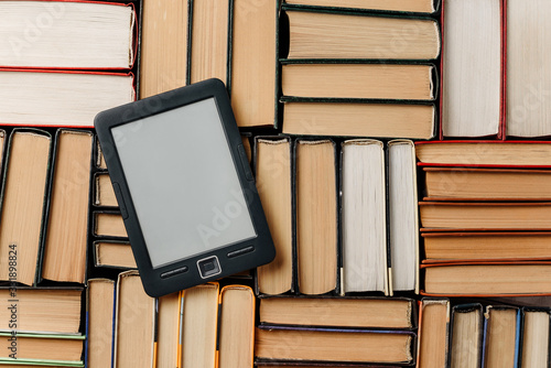composition with an e-book lying on top of paper books.