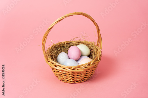 Happy easter: basket with colorful eggs on a pink background.