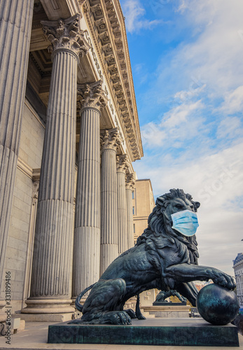Bronze lion statue in front of the Spanish Parliament wearing a face mask as a symbol of the Madrid and Spain lockdown caused by coronavirus outbreak.. photo