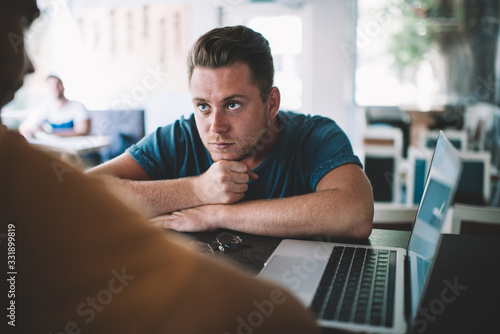 Pensive male leaning on hands in cafe