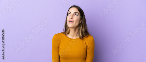 Young caucasian woman over isolated background looking up and with surprised expression