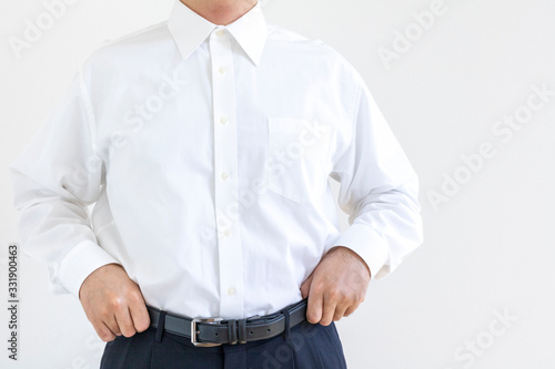 下がったズボンを直しているワイシャツの男性 © poko42