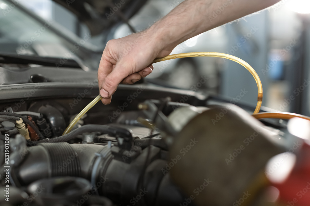 Close up hand of a man in repair shop draining Brake fluid through pipe