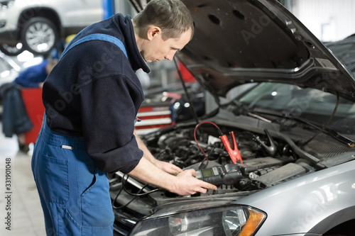 Mechanic examining under hood of car at the repair garage Car service mechanic repairing and maintenance Car. auto mechanic man or smith with wrench at workshop