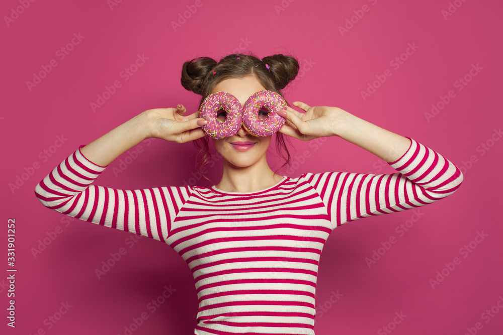 Smiling woman holding donut on colorful pink background, diet concept Smiling woman holding donut on colorful pink background, diet concept