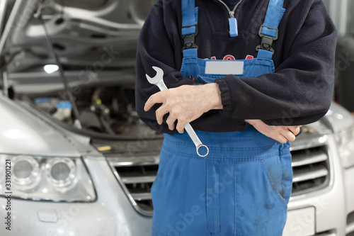 The mechanic with the arms of the cross with a automotive maintenance is background.