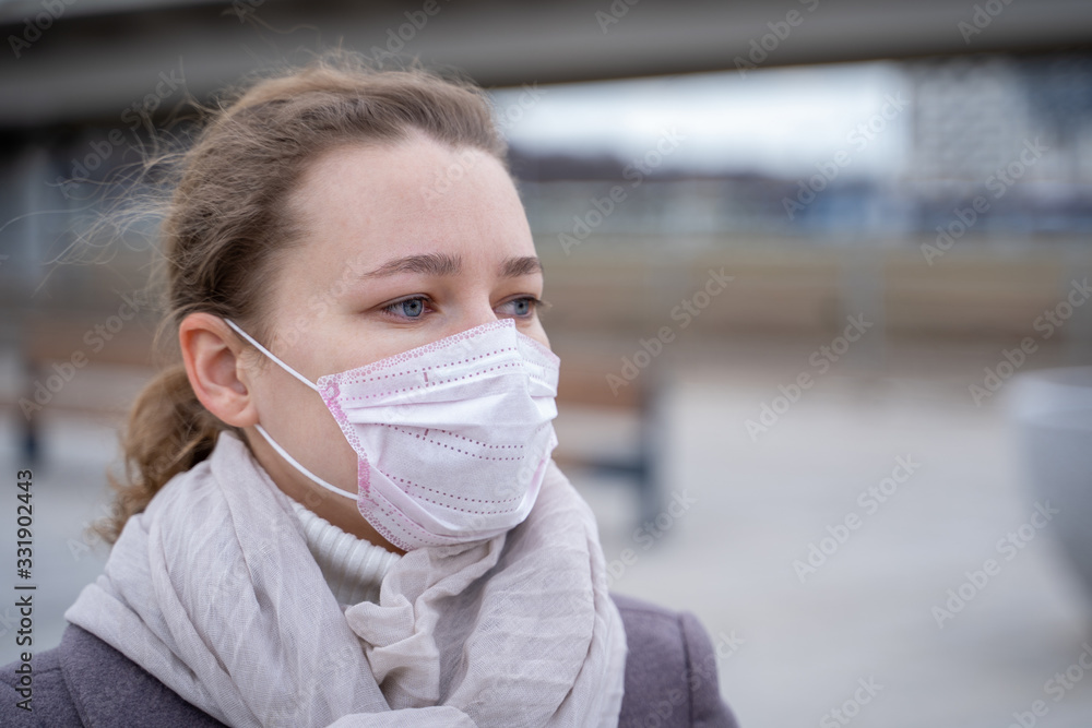 portrait young European woman in protective disposable medical mask in deserted city street outdoor. concept of coronavirus influenza covid-19 quarantine and people panic portrait young European woman in protective disposable medical mask in deserted city street outdoor. concept of coronavirus influenza covid-19 quarantine and people panic