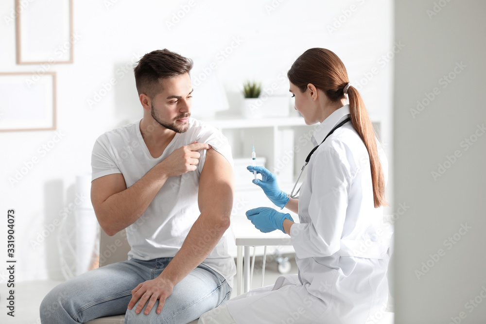 Fototapeta premium Doctor giving injection to patient in hospital. Vaccination concept