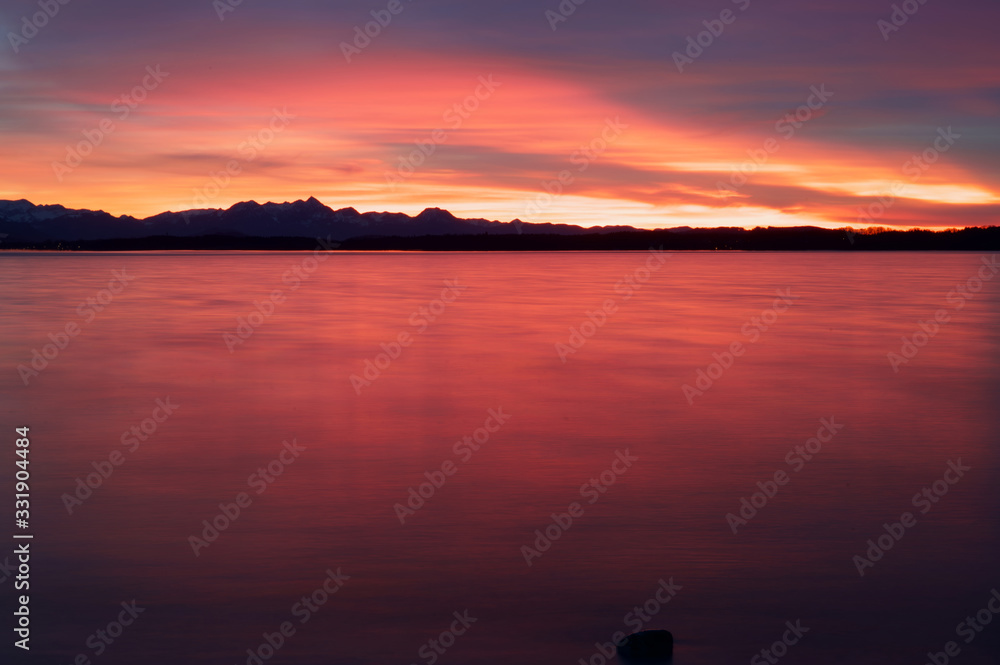 Fototapeta premium Glühendes Abendrot mit Blick auf die Alpen am Chiemsee nach dem Sonnenuntergang